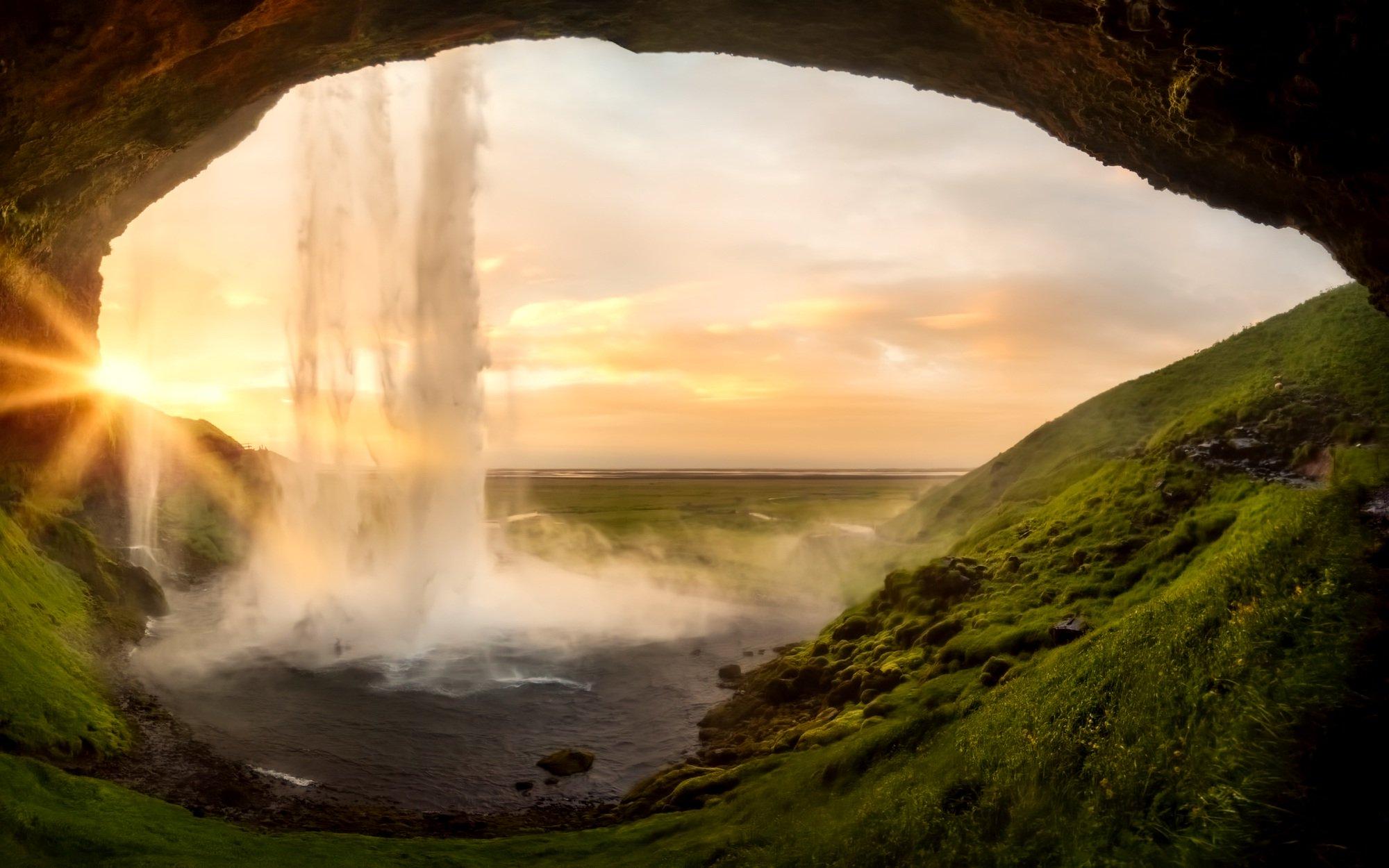 Inside a cave looking out toward a waterfall.