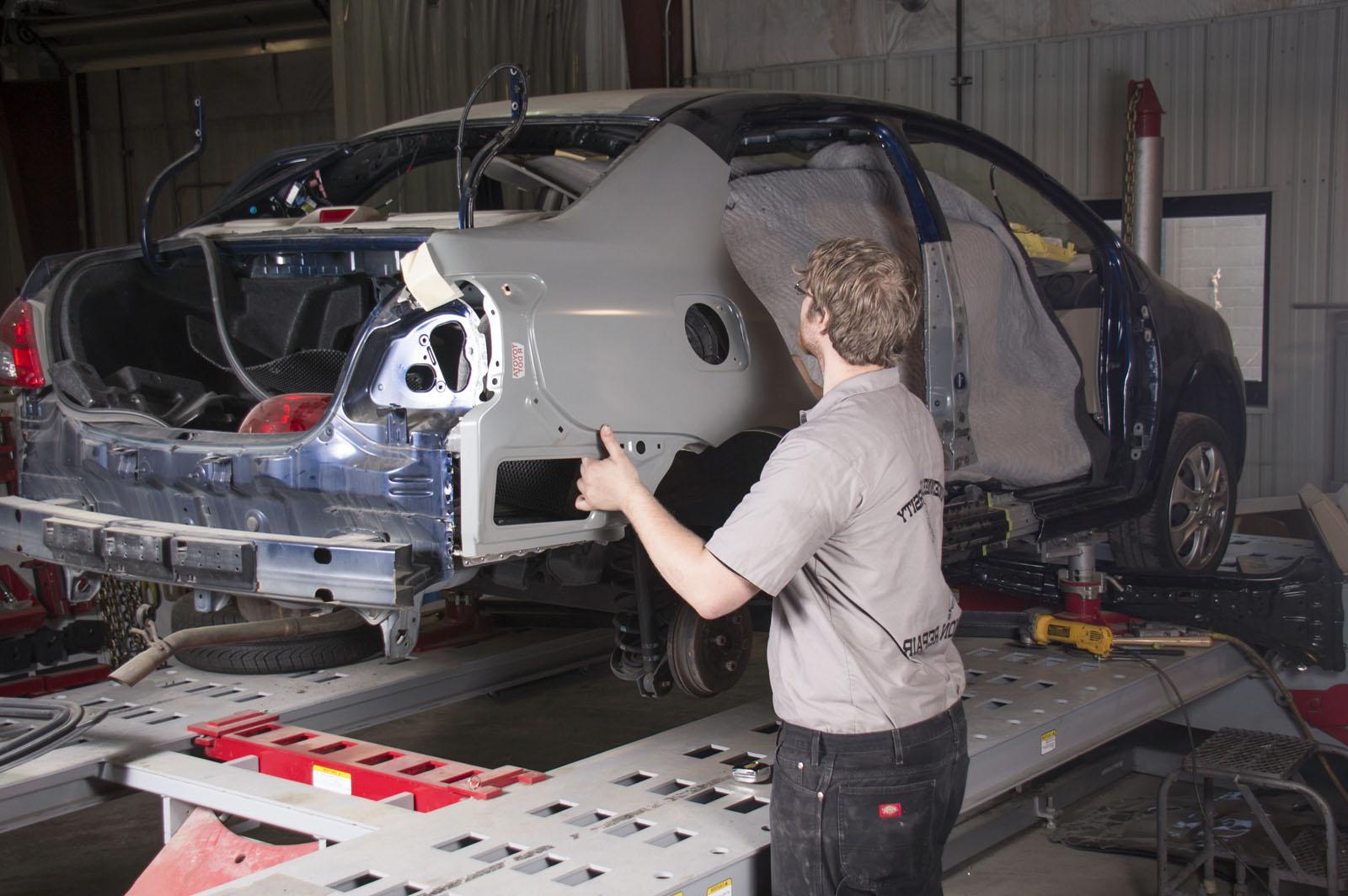 Person repairing damaged automobile panel.